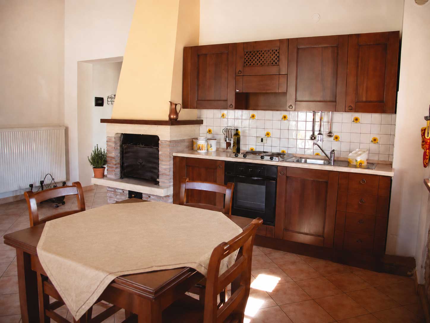 Accogliente cucina rustica dell'appartamento Girasole in agriturismo umbro Domus Santa Croce,  con camino, mobili in legno e atmosfera calda, ideale per turisti italiani.