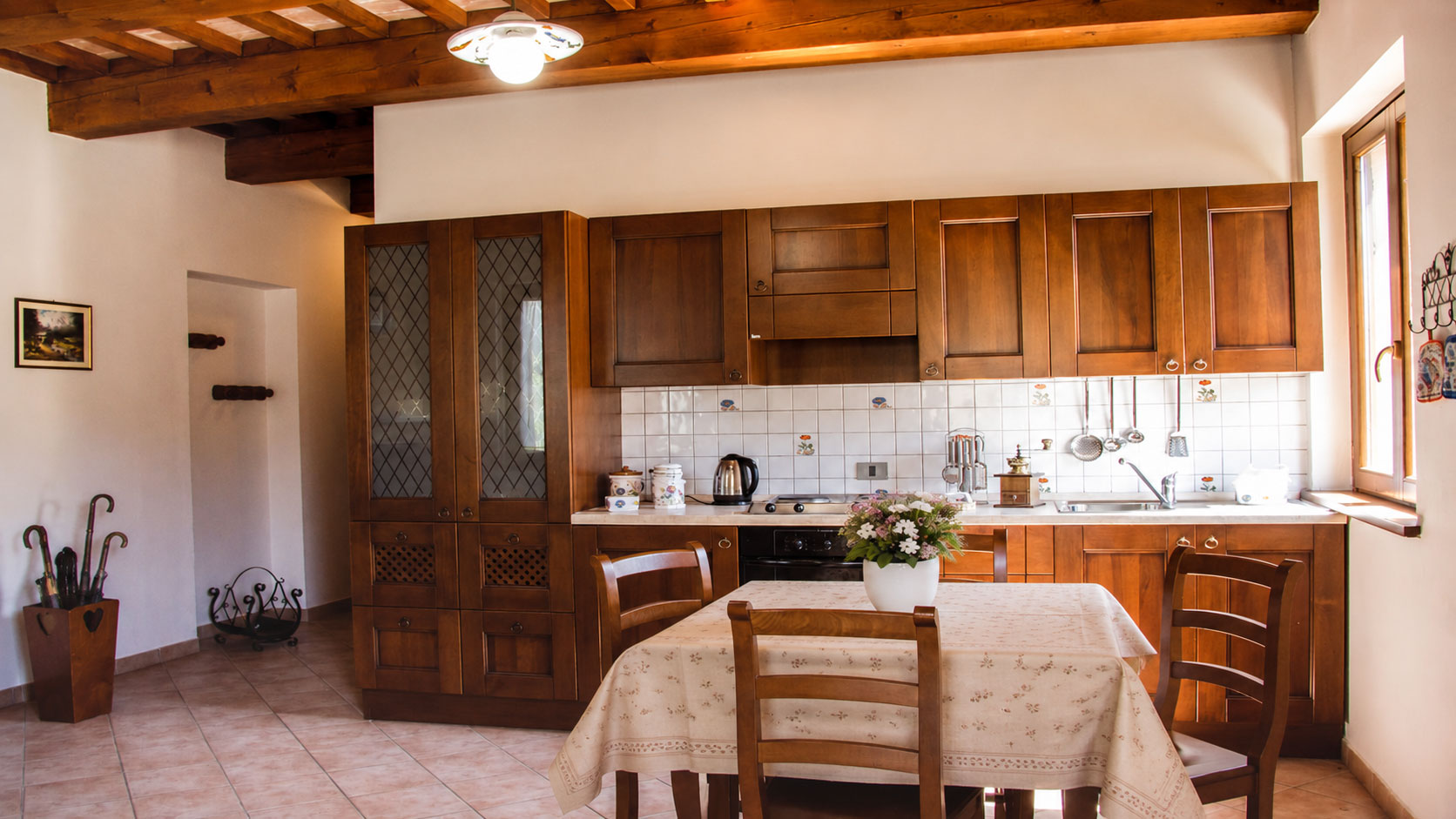 Cucina rustica dell'appartamento Margherita, in  agriturismo umbro Domus Santa Croce. Sono visibili gli arredi in legno, tavolo apparecchiato e dettagli tipici per un soggiorno accogliente.
