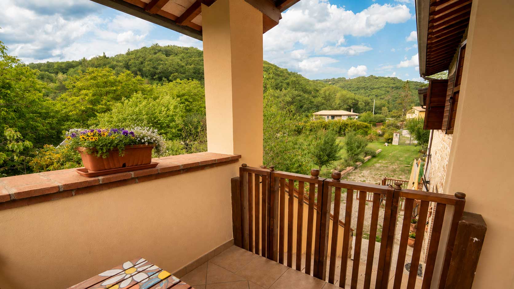 Terrazzo rustico con vista su colline umbre, immerso nel verde, ideale per rilassarsi in agriturismo autentico.