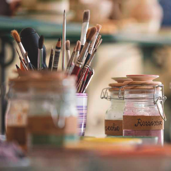 Pennelli artistici e barattoli di pigmenti per laboratori creativi in un agriturismo umbro, ideale per turisti italiani.