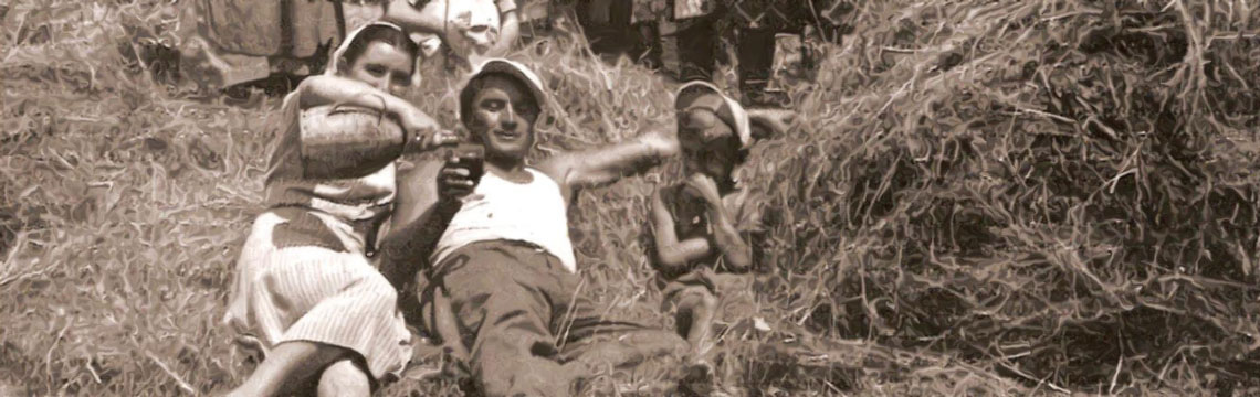 Storica scena agricola umbra: contadini italiani si riposano in un campo di mietitura sotto il caldo sole estivo.