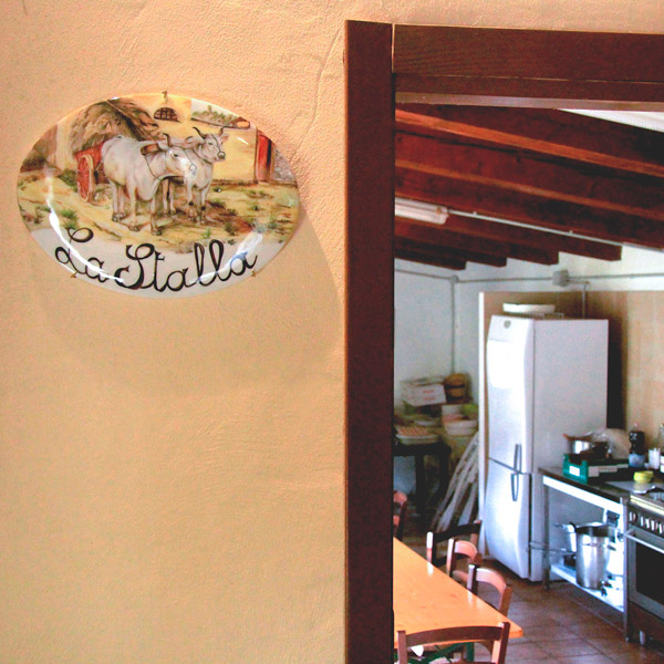 Interno accogliente di un agriturismo umbro con cucina rustica e decorazione La Stalla sul muro.