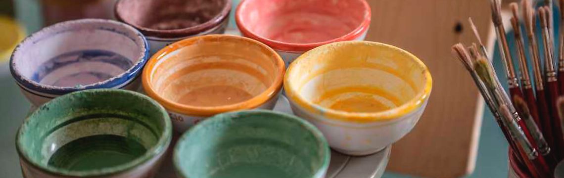 Colori vivaci in ciotole di ceramica per laboratori artistici nell'agriturismo umbro, immersi nella tradizione locale.
