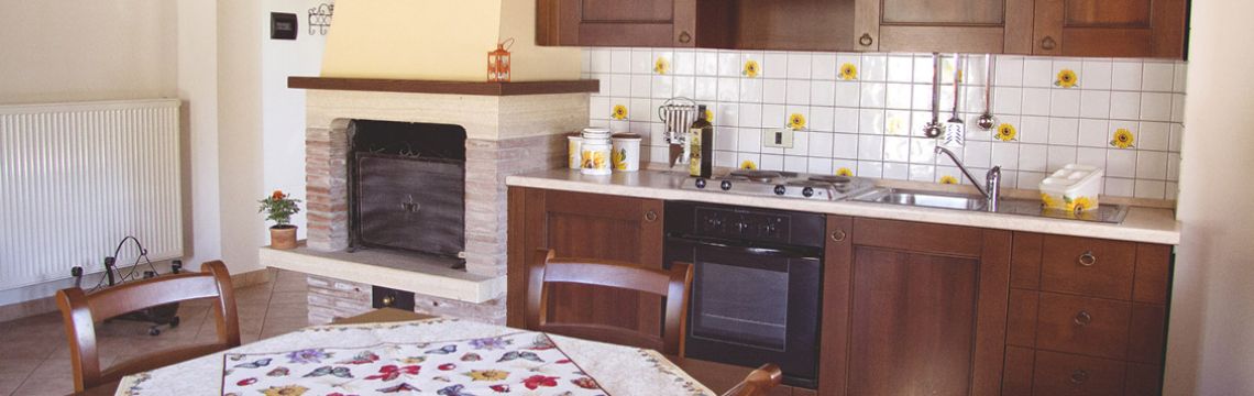 Cucina rustica di agriturismo umbro, con camino e arredi in legno, ideale per turisti italiani in cerca di autenticità.