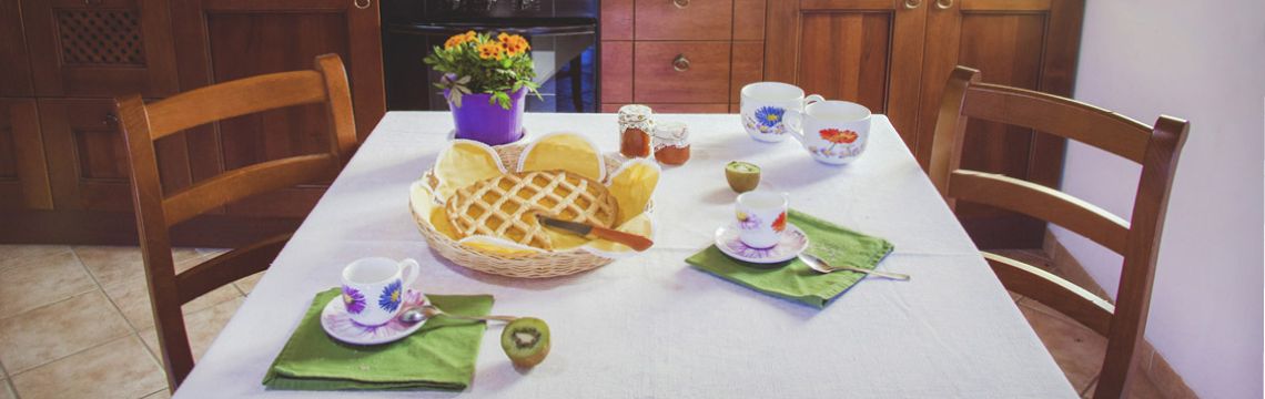 Colazione tipica in agriturismo umbro: crostata, caffè, frutta fresca e atmosfera accogliente per un soggiorno indimenticabile.